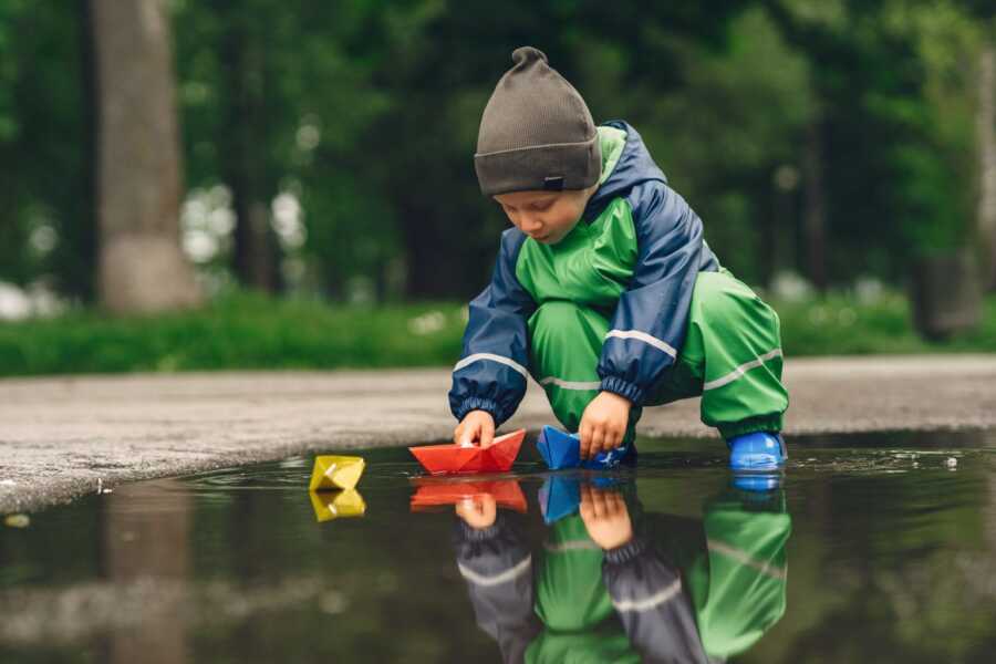 kids pushing boats in the puddles