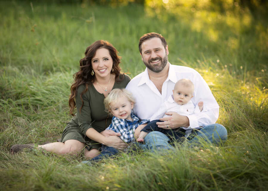 family sits with their two children, one has a limb difference