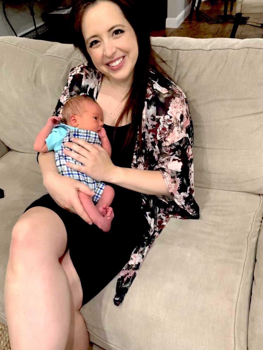 mom holds her newborn with limb difference on lap