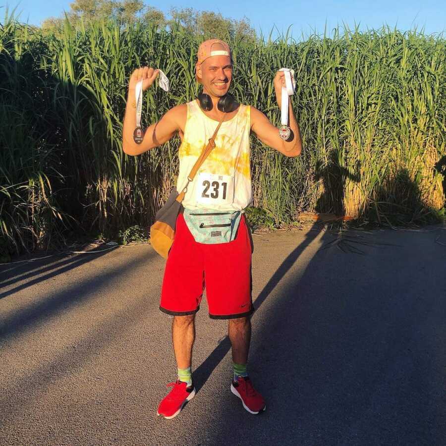 Man holding up race medals and smiling 