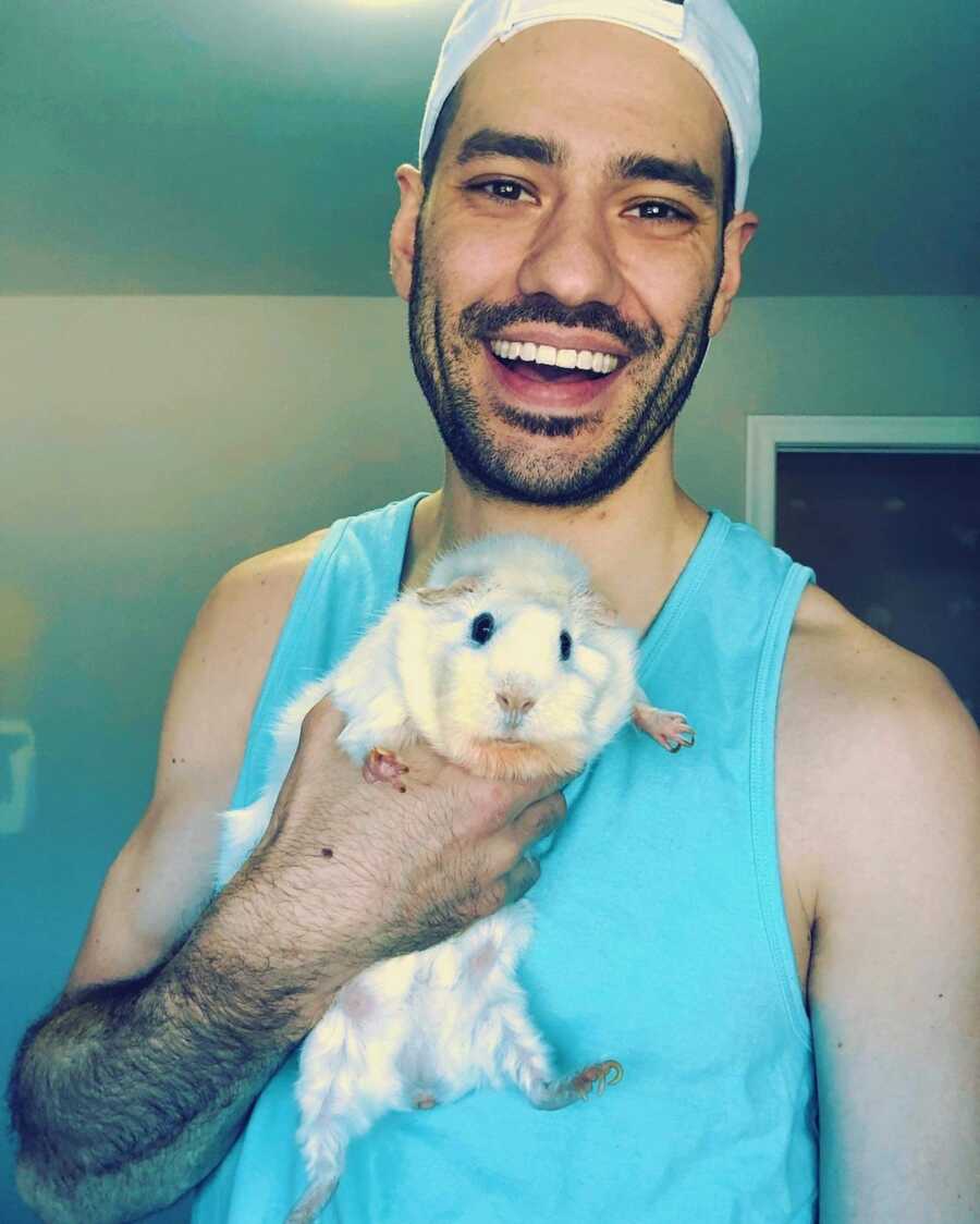 man smiling with guinea pig in arm