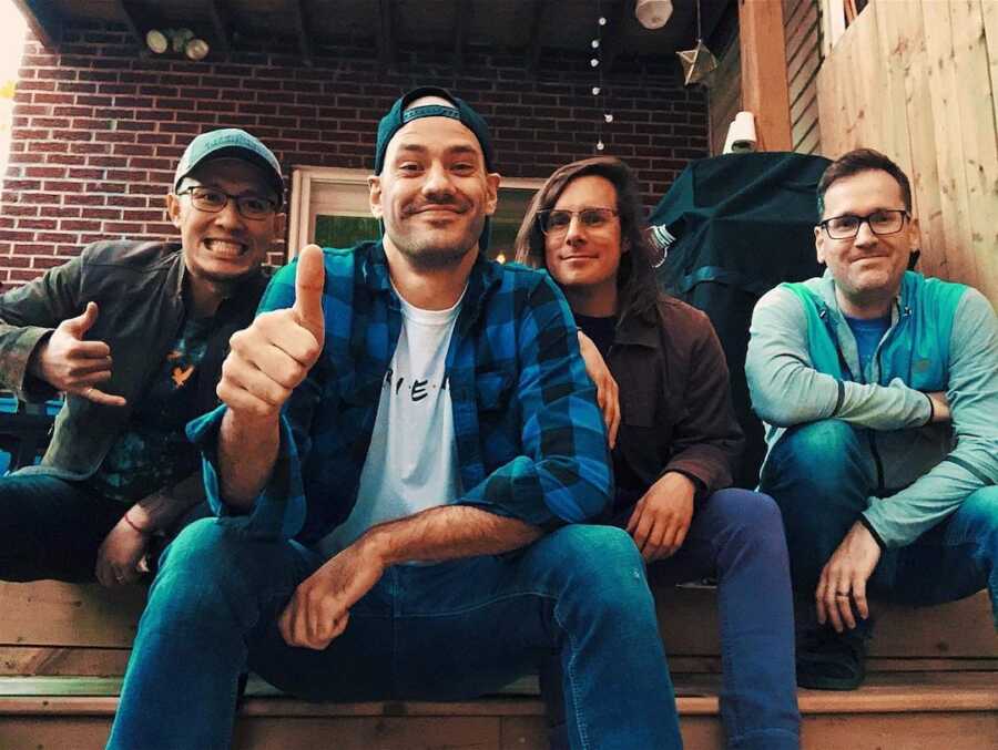 A group of men sitting on steps smiling 