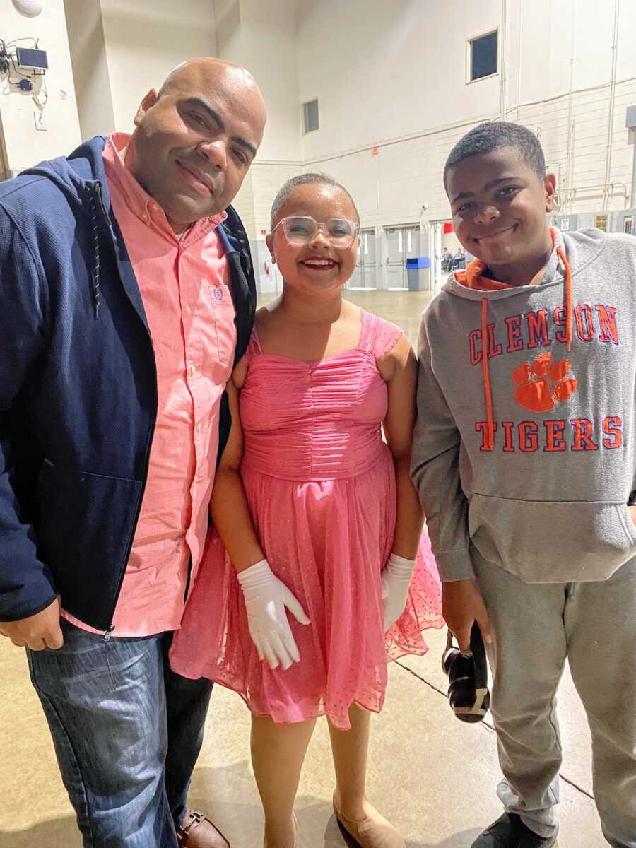 father stands with his two kids at his daughters dance recital
