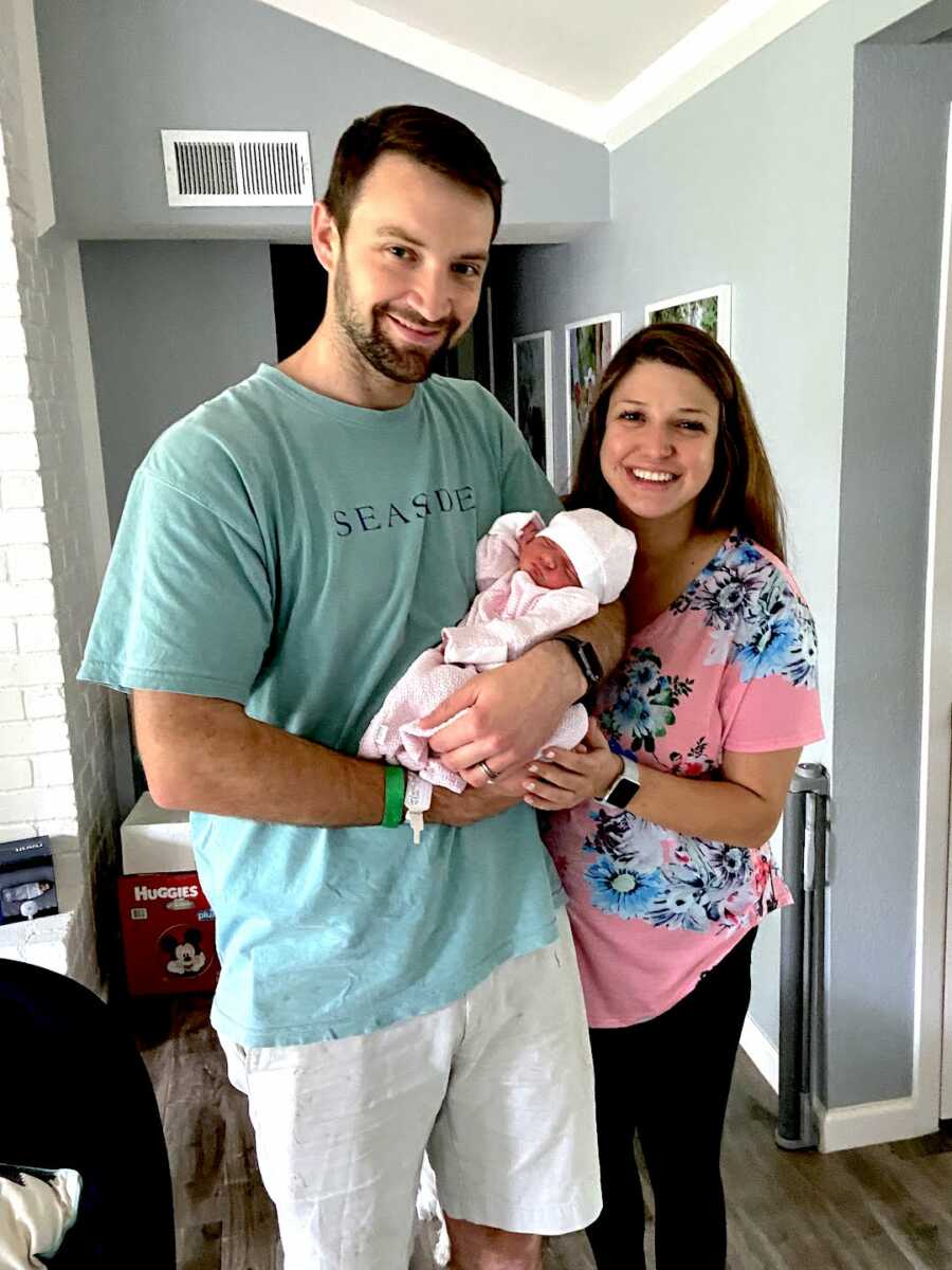 parents hold their newborn daughter who has a limb difference