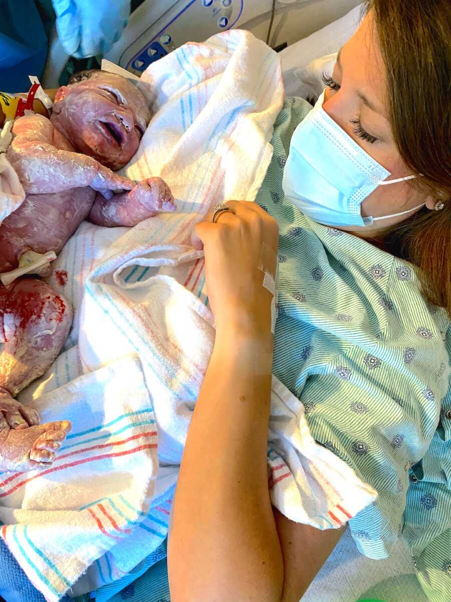 mom lays in bed with newborn on chest, noticing limb difference