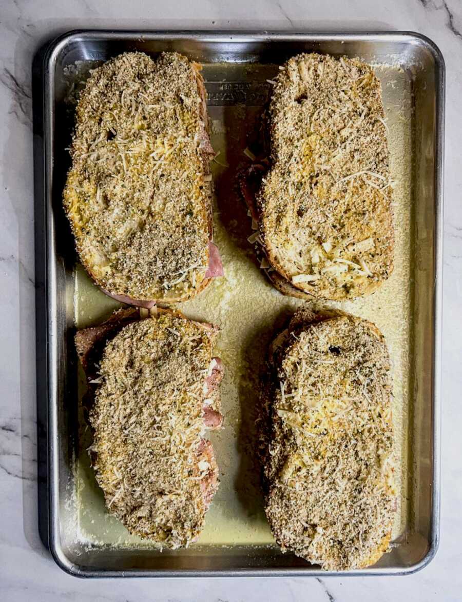 four coated sandwiches placed onto buttered sheet pan