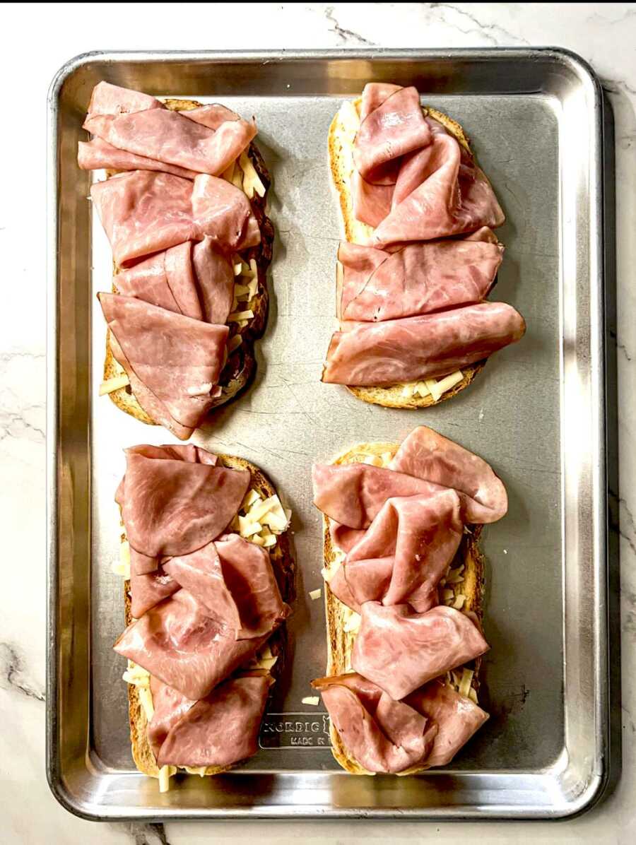bread on pan with cheese and ham on top