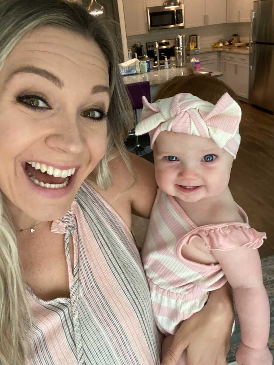 Single foster mom takes selfie with baby girl wearing giant bow headband.