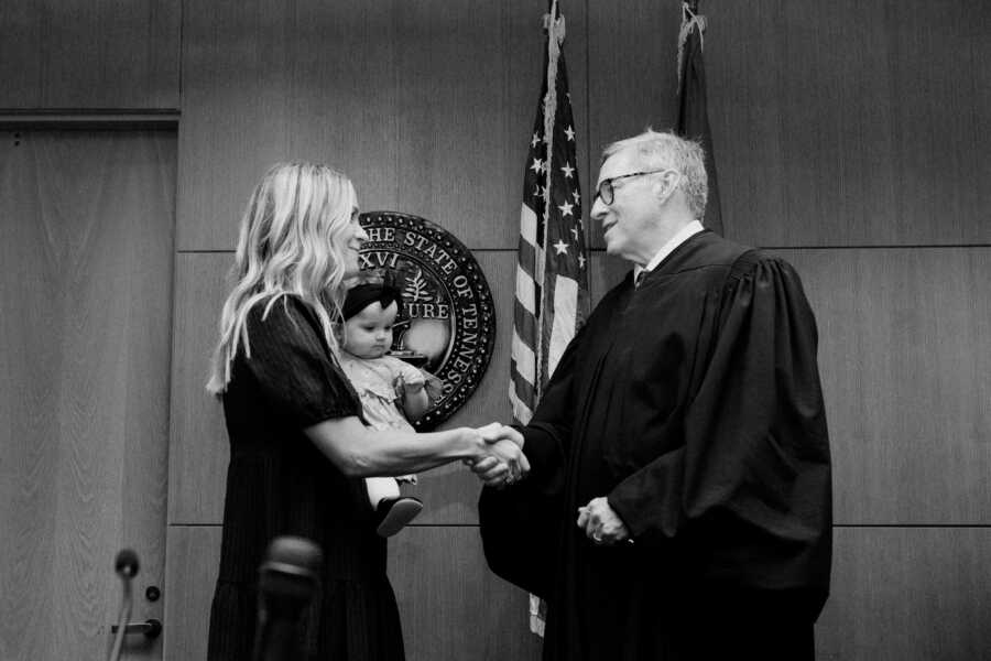 Single foster mom shakes hands with the judge on the adoption day of her baby girl.