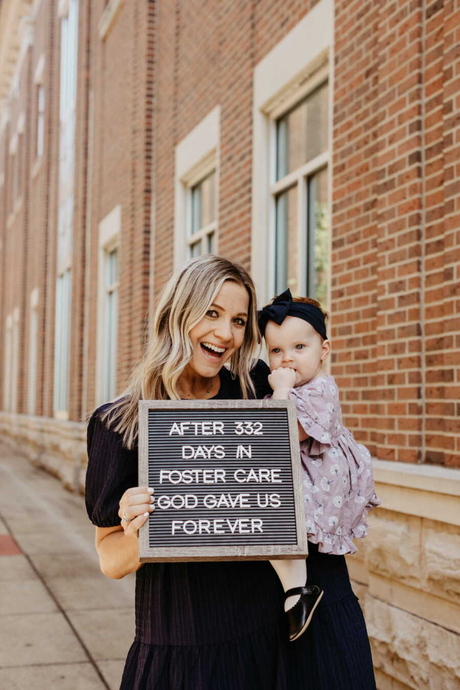 Single adoptive mom holds up sign and baby girl on adoption day.