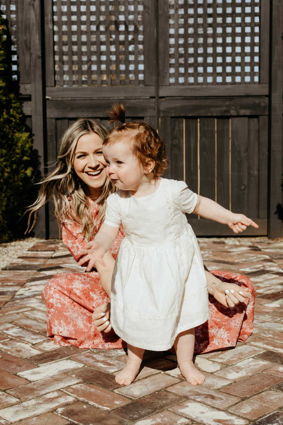 Single adoptive mom watches toddler girl as she moves around in excitement.