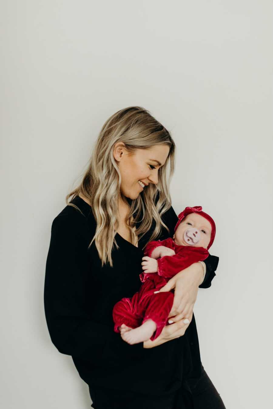 Single foster mom looks lovingly at baby girl she's holding in her arms.