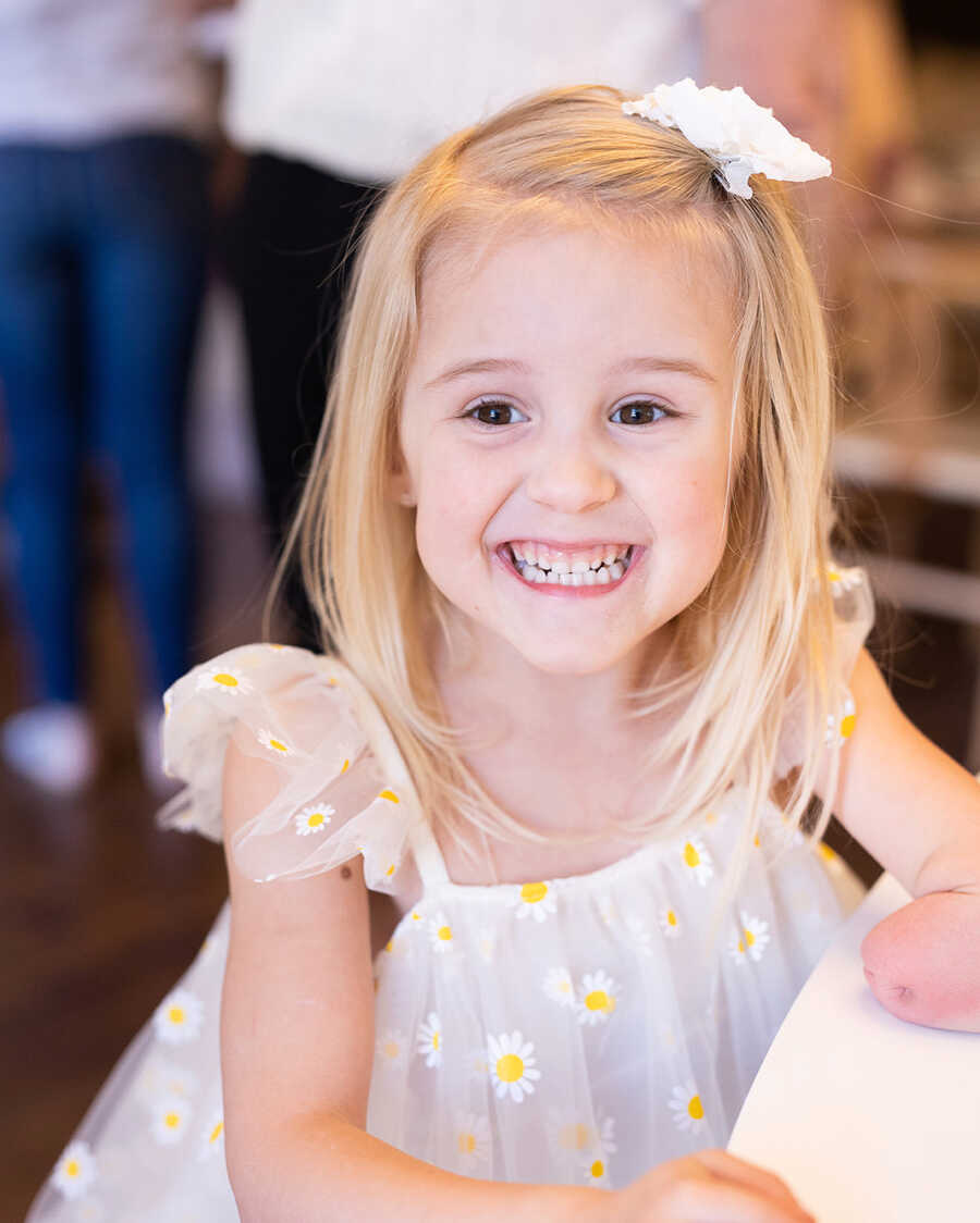 Adorable little girl with limb difference gives big smile.
