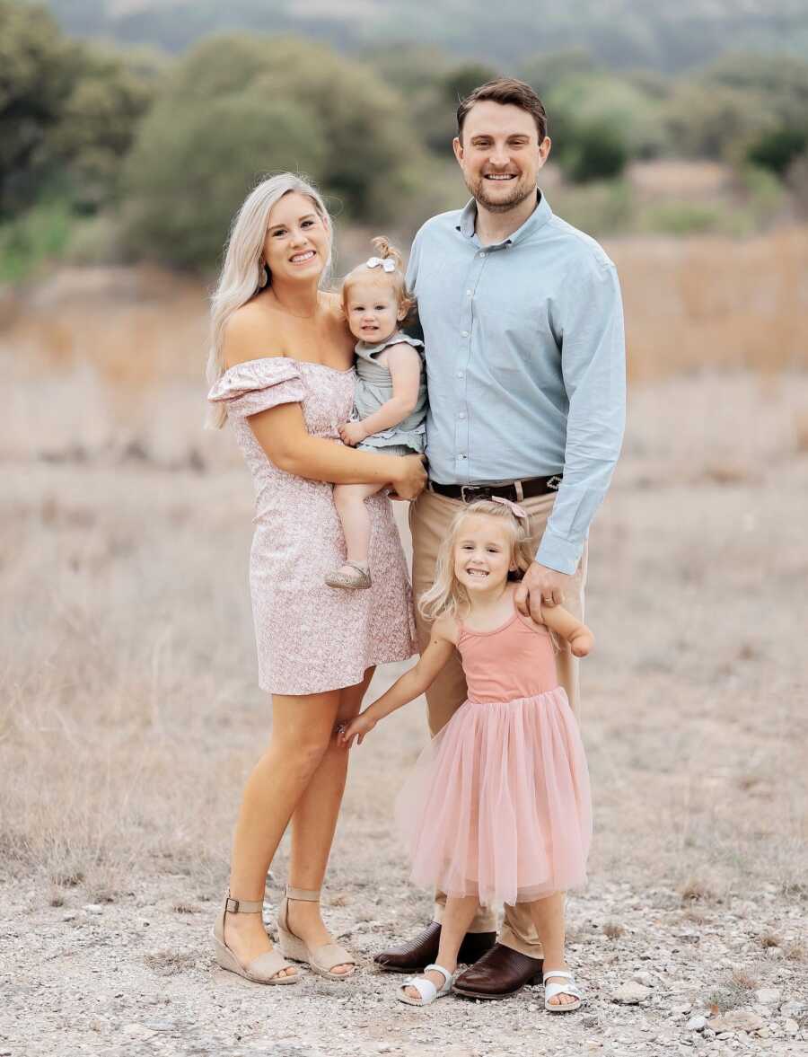 Couple takes family picture with two young daughters.