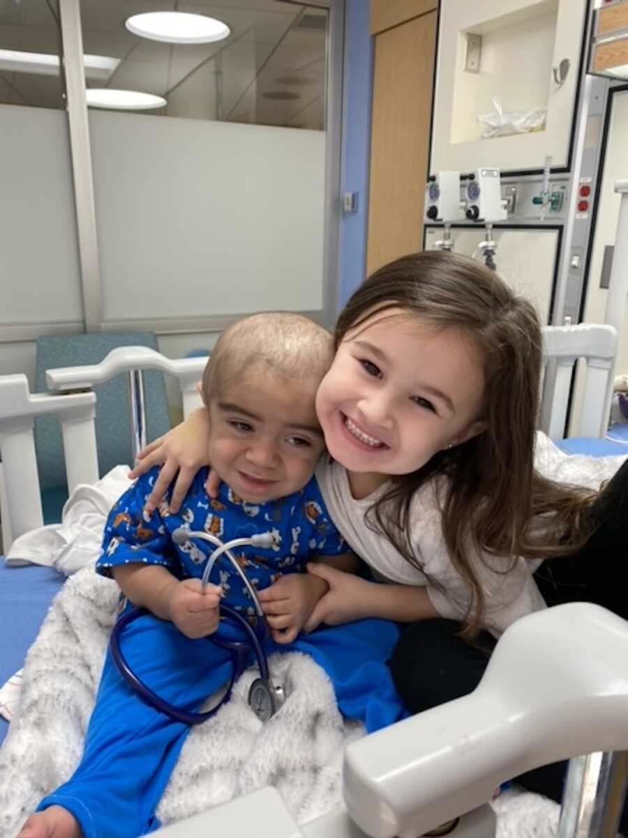 big sister gives her little brother a big hug while in the hospital