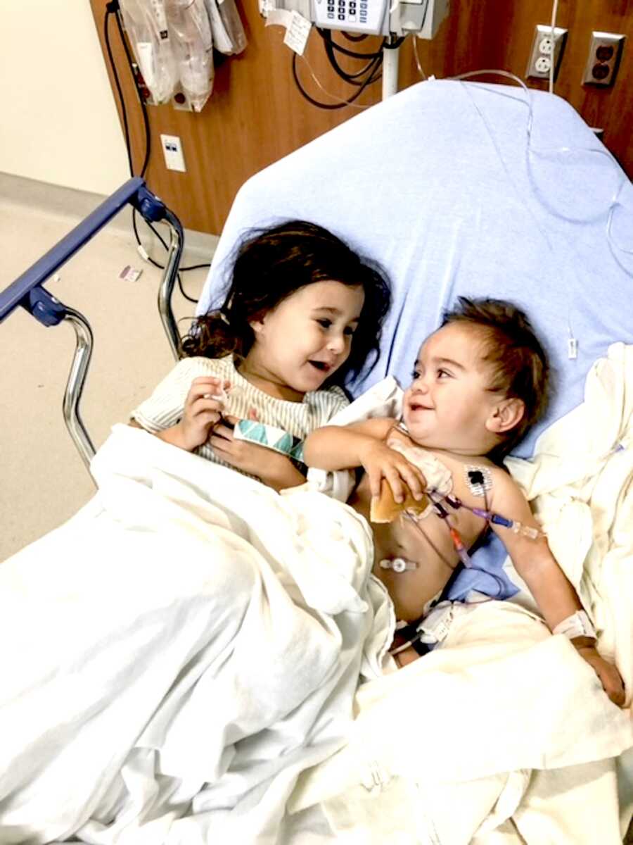 siblings lay next to each other in a hospital bed