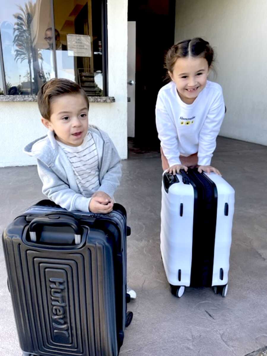 two children, daughter and son, stand with their luggage
