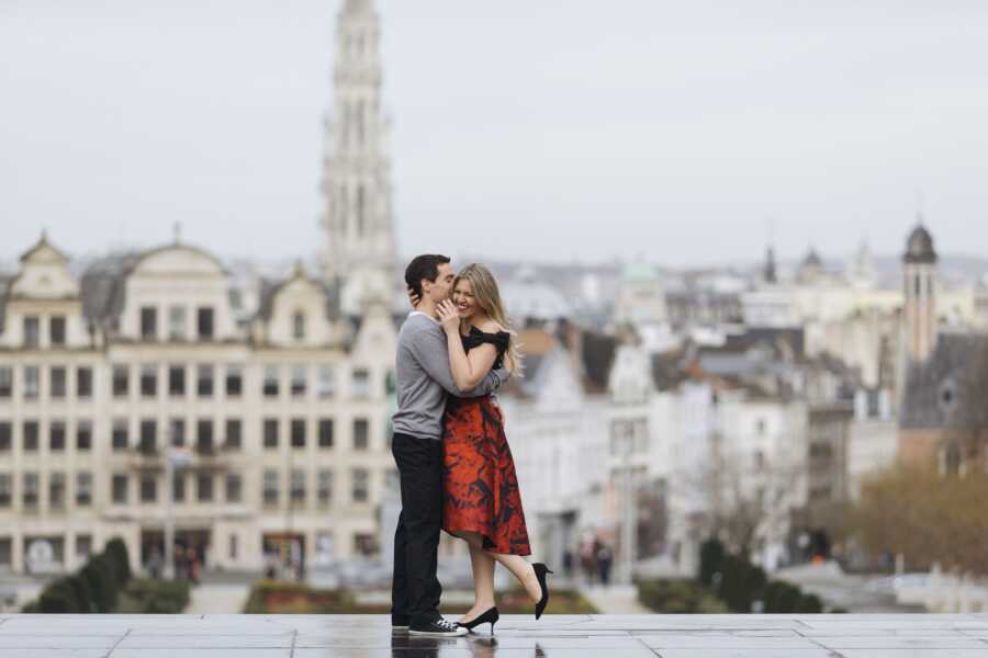 husband embraces wife tightly in a hug, she smiles