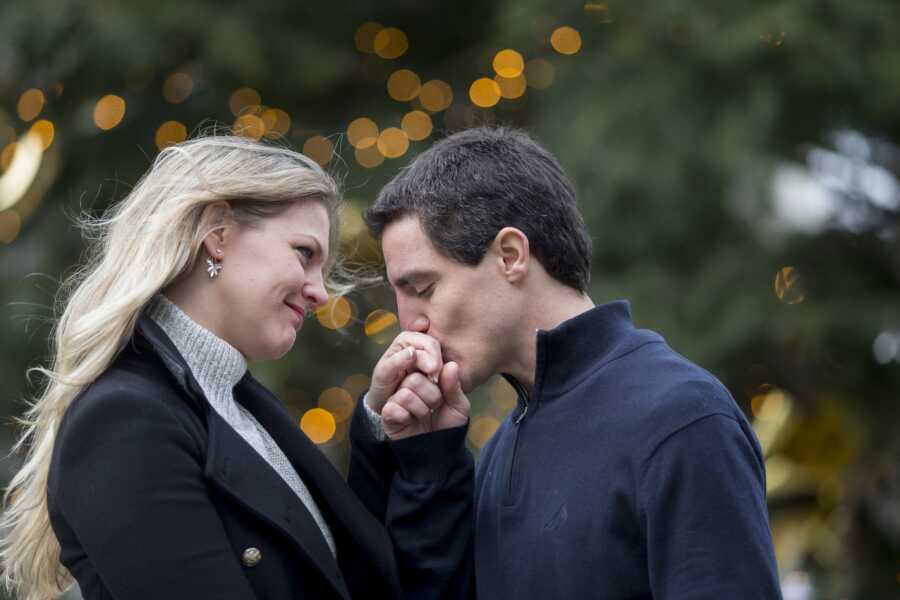 husband takes wife's hand and gives it a kiss