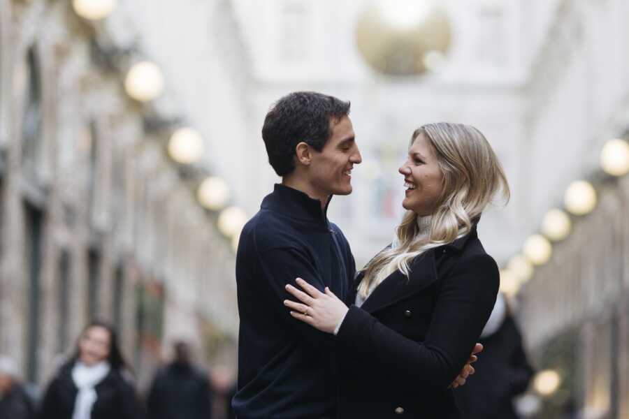 Husband and wife smile at each other while facing and holding each other close.