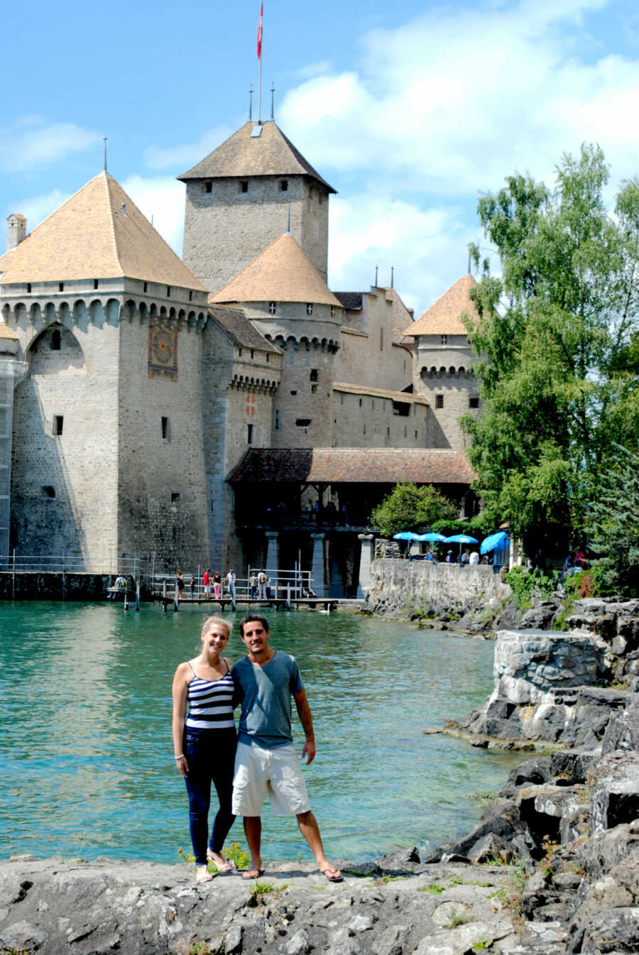 husband and wife pose together in front of a castle