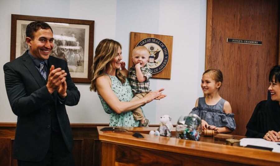 Foster family stands in court room to adopt young boy.