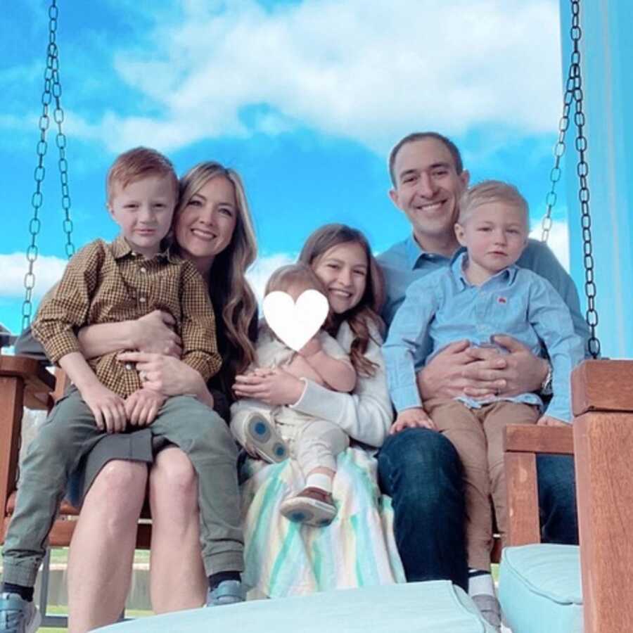 Family continues to foster and takes picture on porch swing with current children.