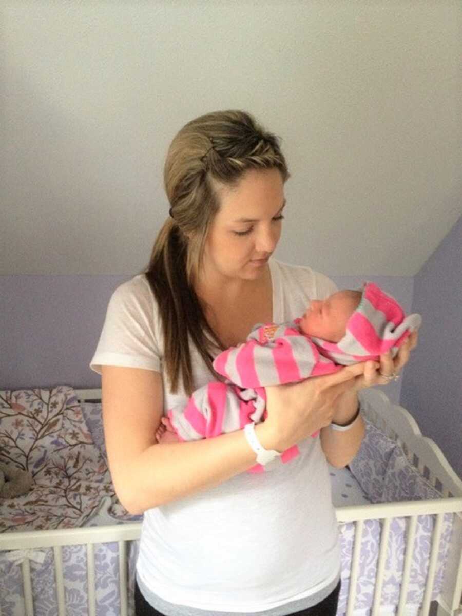 Freshly postpartum mom holds new baby girl at home.