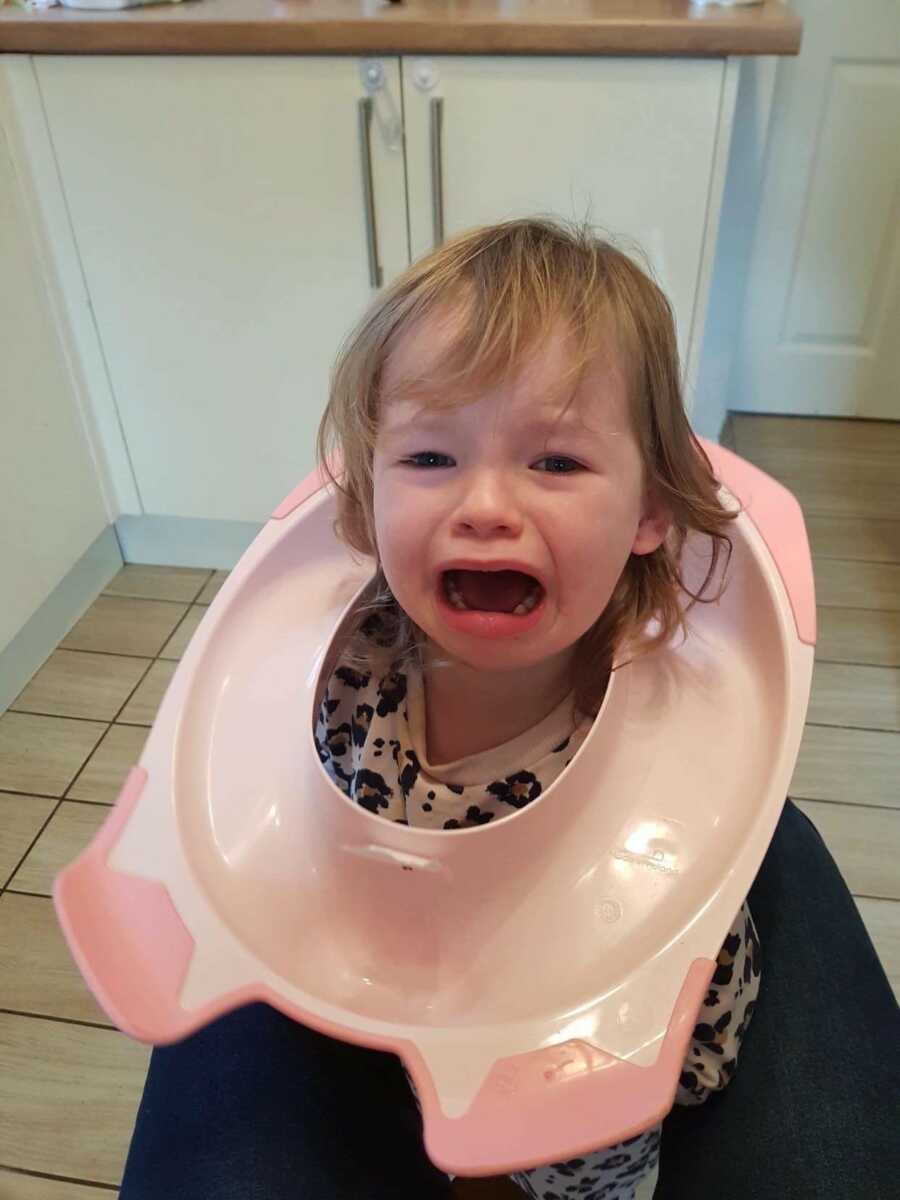 daughter with a toilet seat around her head