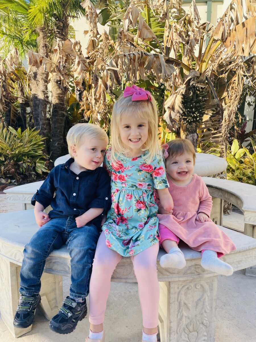 Three children with limb differences take picture outside together.