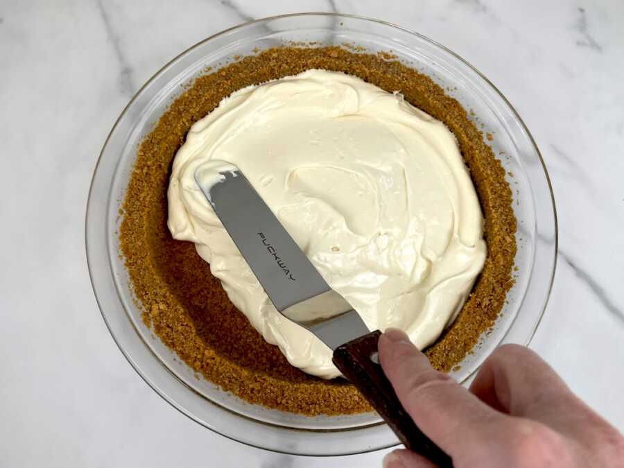 spreading cheesecake mixture into the cooled crust