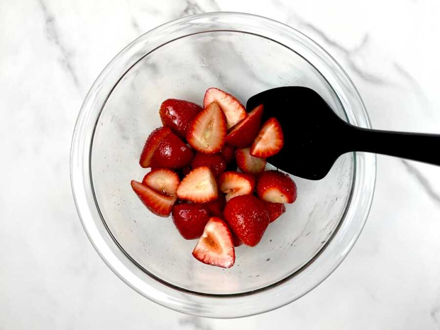mixing the strawberries in a bowl to prepare them for topping