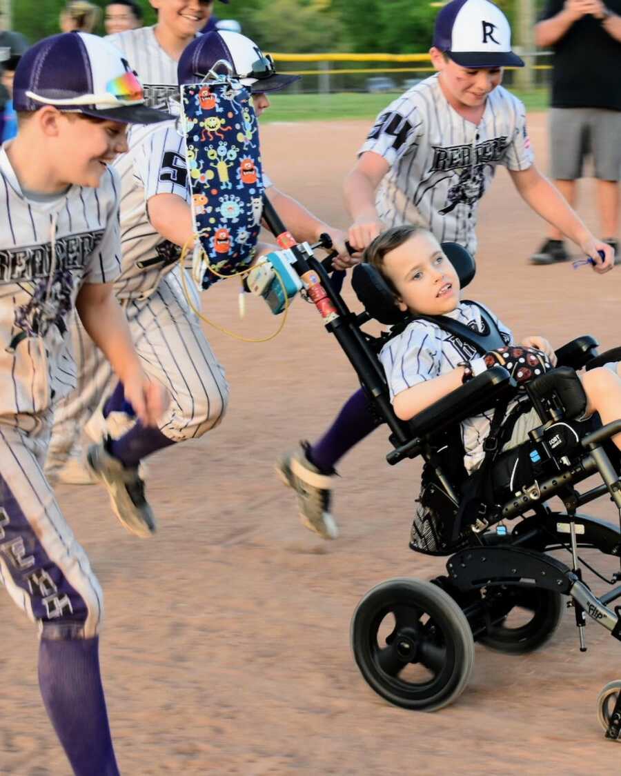 baseball players run young boy with disability across the field