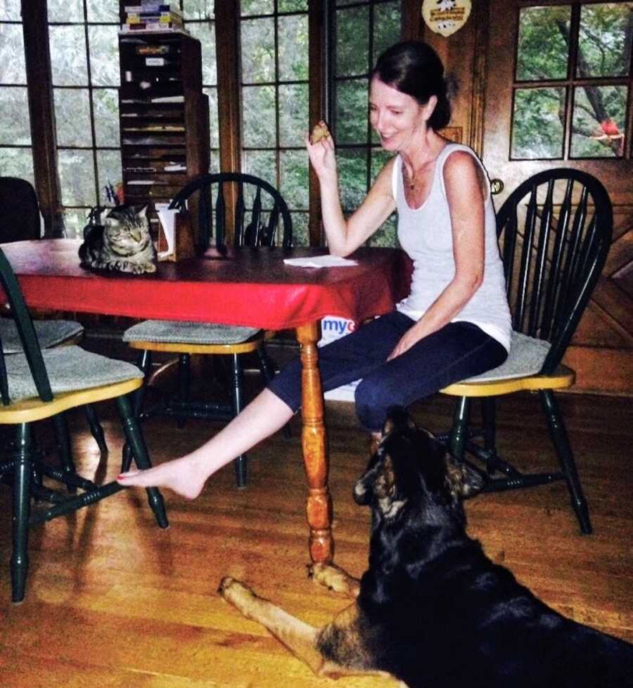 woman with chronic lyme sits at kitchen table with dog and cat nearby