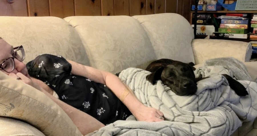 woman with lyme lays on couch cuddled up with her dog