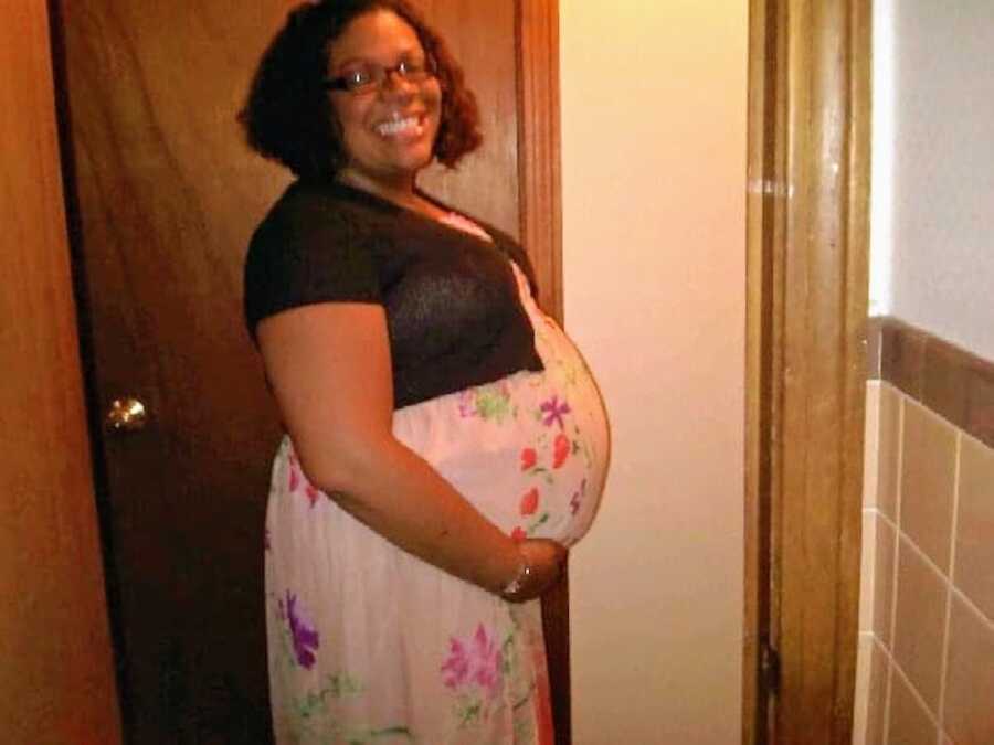 mother poses with her belly bump while in a dress