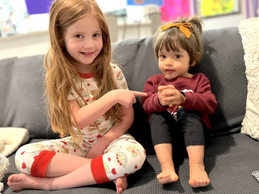 big sister sits on couch with adopted little sister