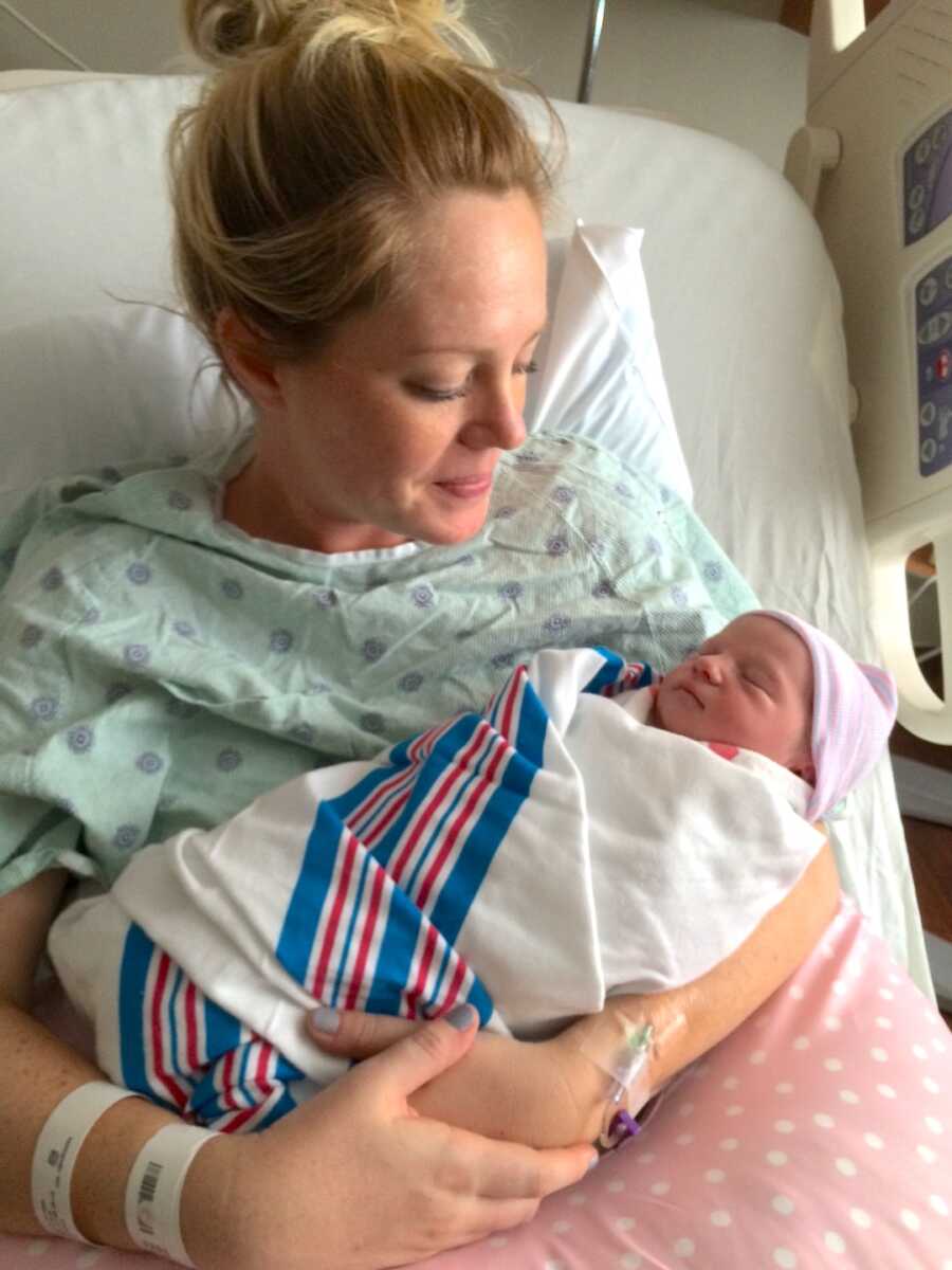 mom sits in hospital bed holding newborn daughter