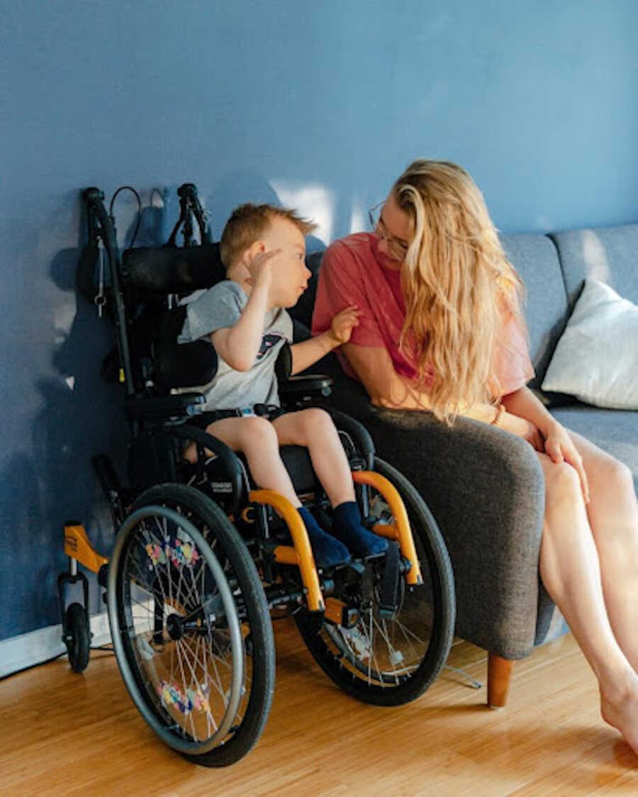 boy in wheel chair next to mom in chair