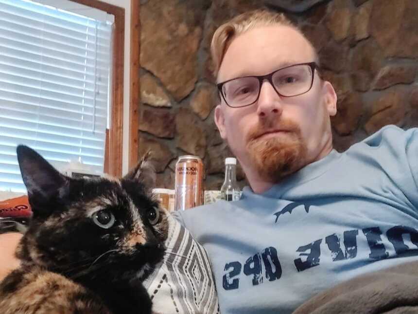 A man sits on the couch with his cat