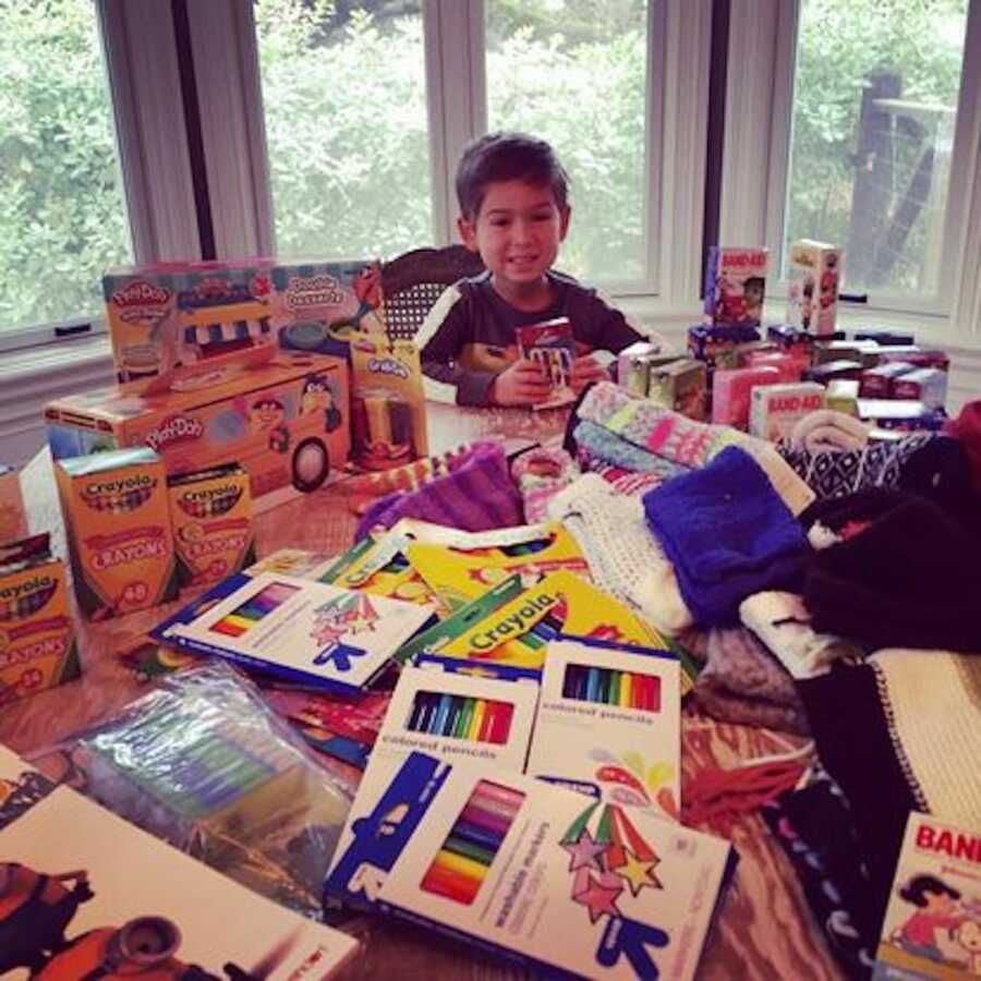 young boy sitting at end of table with charity items in front 