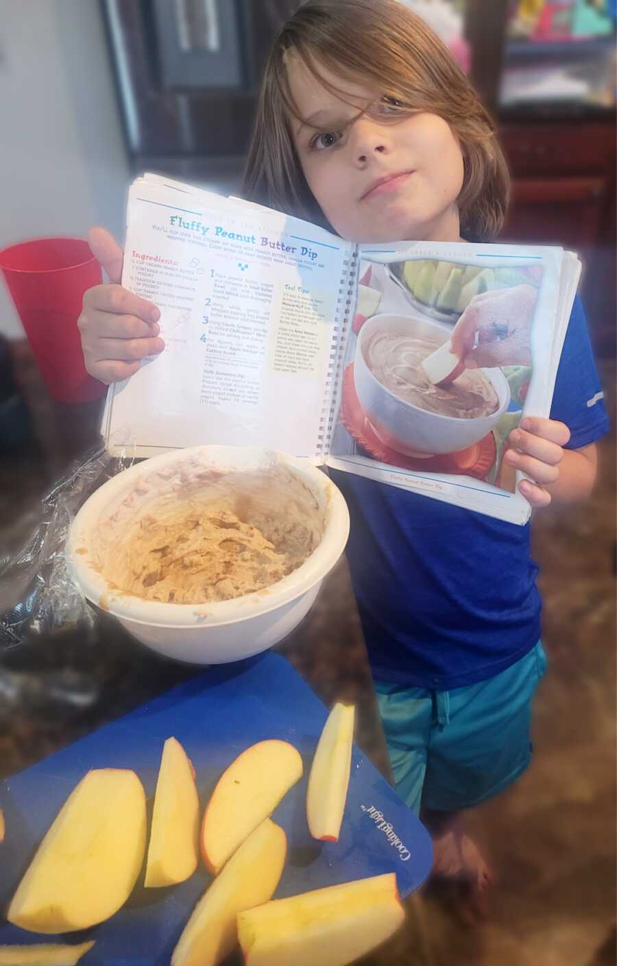 boy with cookbook in hands smiling 