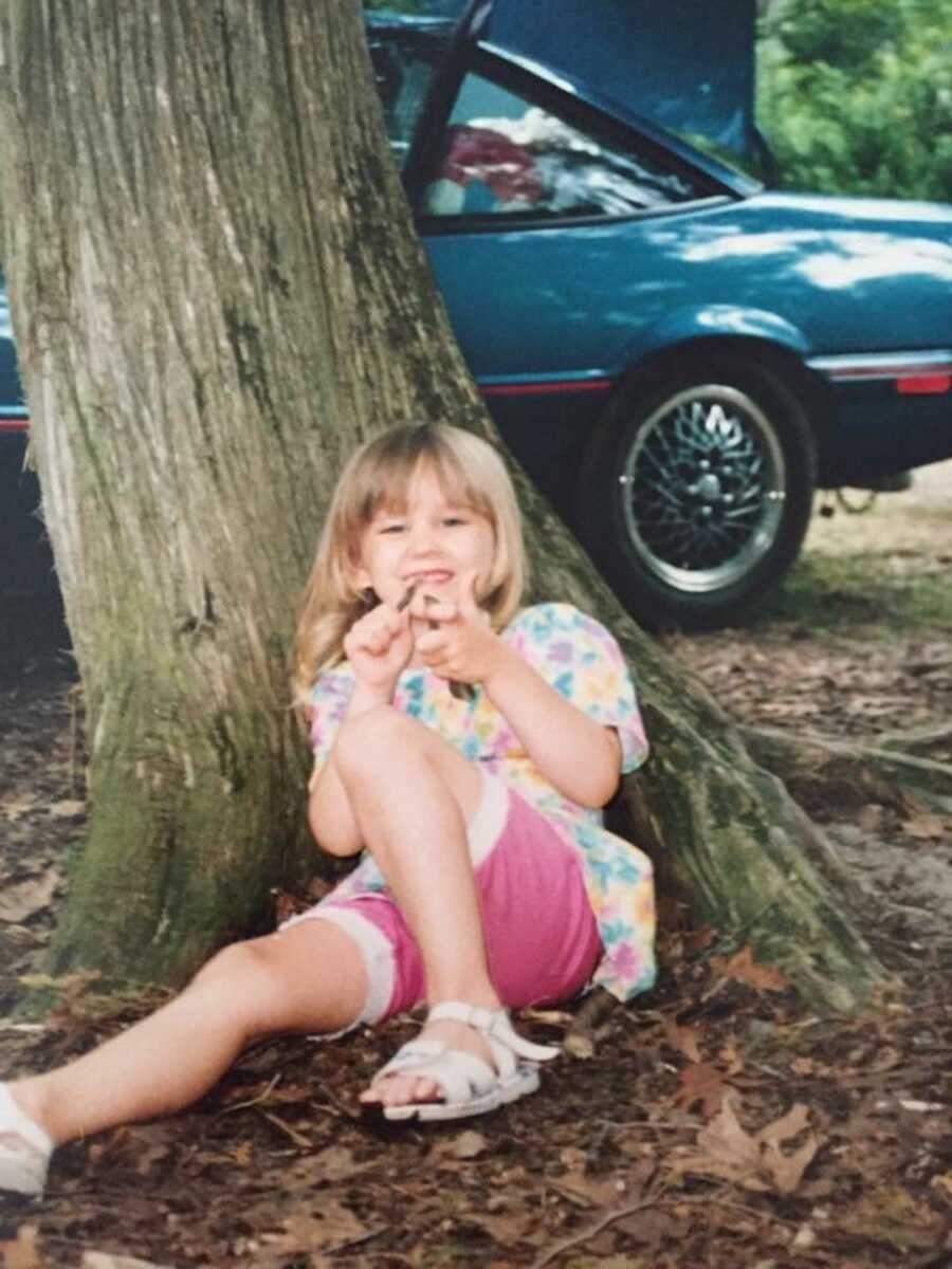 young girl playing in dirt next to tree