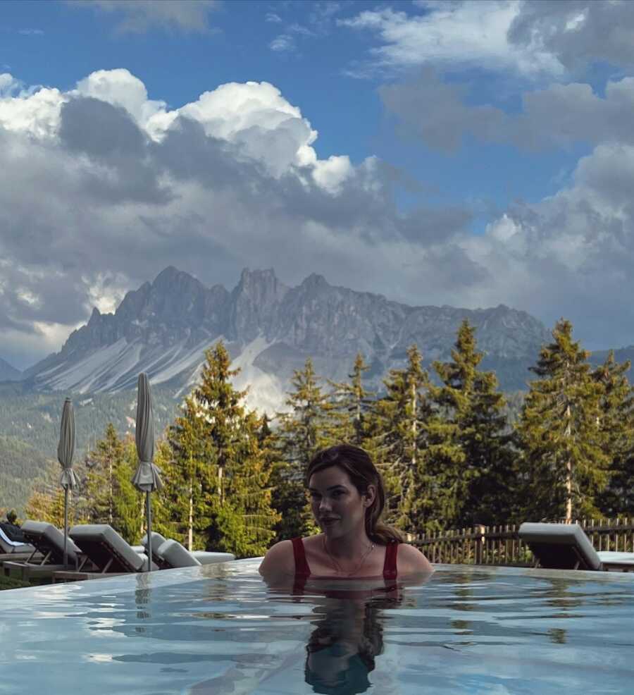 woman in a pool with mountains in background 