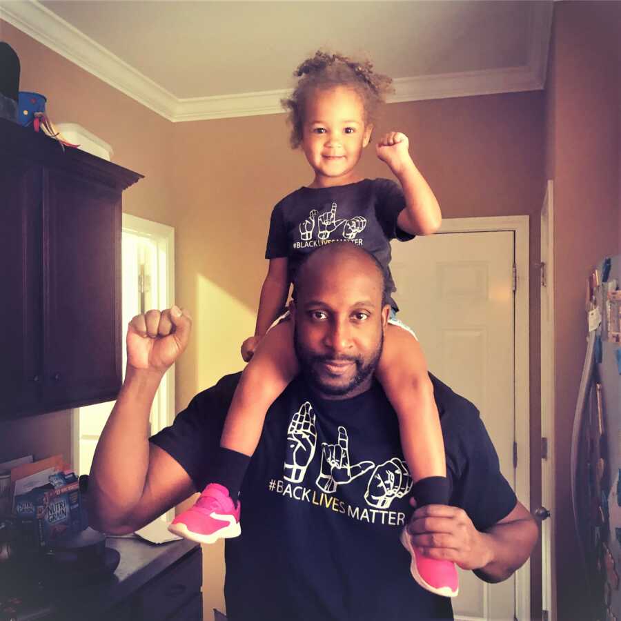 dad holding his daughter who is deaf on his shoulders