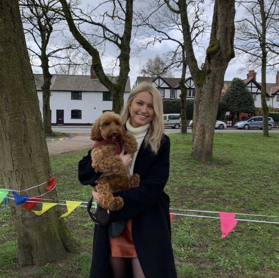 woman standing outside with a dog in her arms 