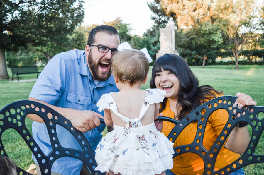 Foster parents playing with their foster daughter with big smiles on their faces 