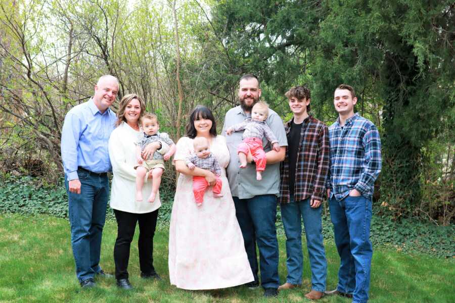 Outdoors family portrait of husband and wife with their three adoptive sons and the rest of their family