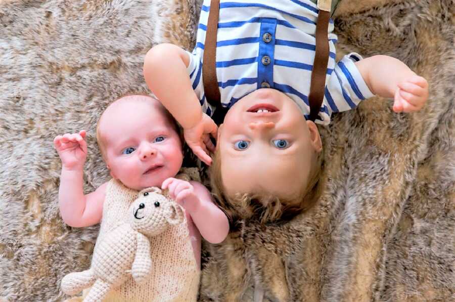 Two adoptive brothers laying on the floor with their heads next to each other's