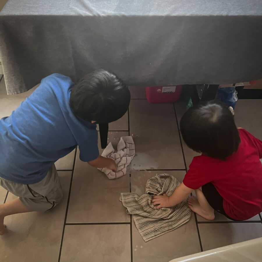 two sons on floor cleaning up spilled milk